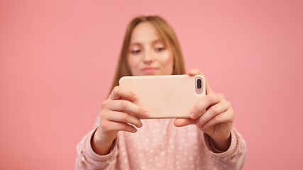 Young caucasian woman using smartphone and taking photos. Isolated on pink background. High quality photo