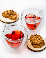 two transparent cups of tea with oat  cookies on white table. vertical image