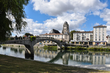 White bridge that crosses a river to reach the city surrounded by a natural landscape
