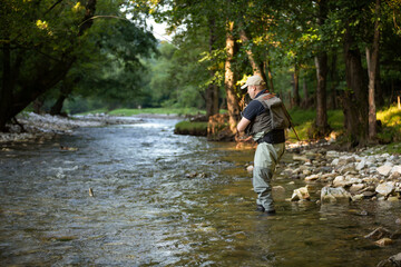 Fototapeta na wymiar Professional fisherman fly fishing at sunrise on a mountain river.