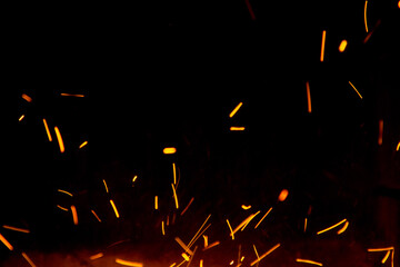 Fire sparks in the air near the forge on black background