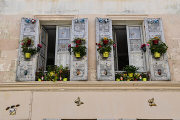 two stone facade windows and decorated with flowers
