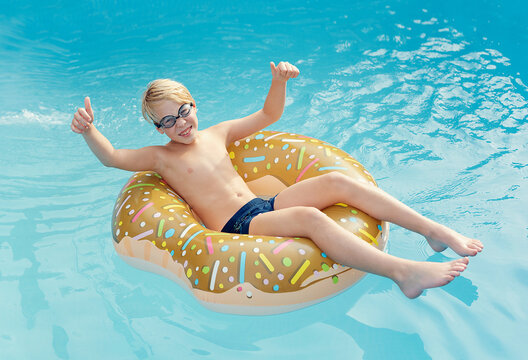 boy splashes in the pool. Summer time, vacation