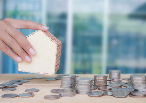 future saving money for 2021 year concept. coin with hond holding model house on wood with blue background. article for buy house for cash nex year.