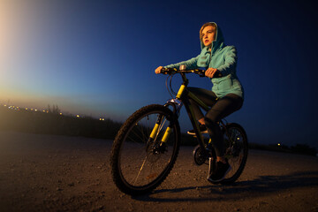 Fototapeta na wymiar Young woman cycling on bicycle at the night