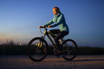 Young woman cycling on bicycle at the night