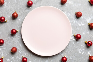 Top view of festive plate with red baubles on cement background. Christmas decorations and toys. New Year advent concept