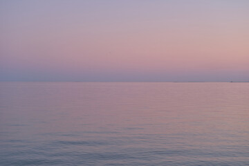 Naklejka na ściany i meble Purple gradient of the sky and sea in the evening. Calm sea wavy surface