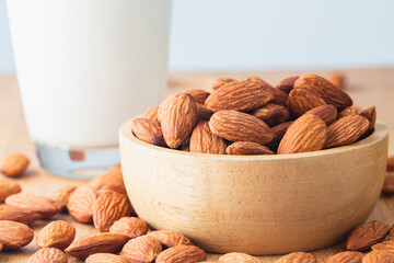 Close up. Almond seeds in a bowl wood and  milk glass on table wooden