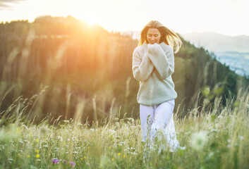 Fototapeta na wymiar Happy woman enjoying sunset stay on the green grass on the forest peak of mountain. Fresh air, Travel, Summer, Fall, Holidays, Journey, Trip, Lifestyle. Health care, authenticity, sense of balance and