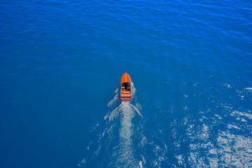 View of the speed boat. A large, orange speedboat moving on blue water. Aerial view of fast boat movement. Lonely boat, movement on the water.