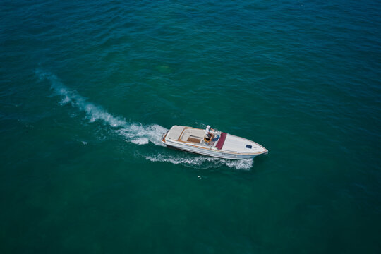 Aerial bird's eye view photo taken by drone of boat. Top view of a white boat sailing to the blue sea.  Motor boat in the sea.Travel - image.