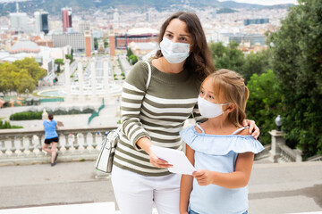 Portrait of a mother and daughter in protective mask on the observation deck of European city