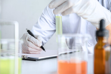 Scientist or medical in lab coat holding test tube with reagent, mixing reagents in glass flask, glassware containing chemical liquid, laboratory research and testing