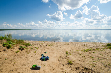 Fototapeta na wymiar Children's shoes on the sandy shore. Summer rest. Sink 