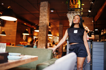 Fototapeta na wymiar Fashionable feminist african american woman wear in black t-shirt and shorts, posed at restaurant.