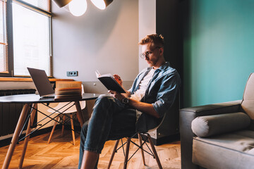 Focused caucasian man college student in glasses studying with books laptop distantly preparing for test exam writing essay doing homework at home, distantly education concept.