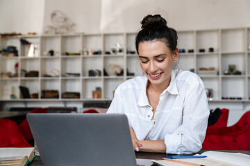 Smiling young woman studying on laptop computer