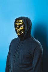 Portrait of a man in a skull mask with a hood on a blue background. Halloween party costume. Vertical orientation