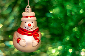 Vintage old Soviet Christmas tree toy (snowman) on the background of a Christmas tree and New Year's multi-colored tinsel.