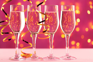 Four champagne glasses against pink background with blurred garland
