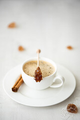 a cup of black coffee with cinnamon and caramelized sugar on a stick
