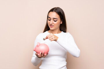 Young woman over isolated background holding a big piggybank