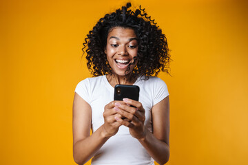 Image of excited african american girl using mobile phone