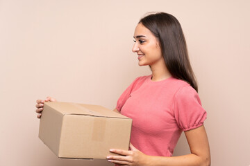 Young woman over isolated background holding a box to move it to another site
