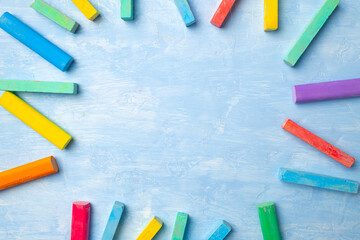 Colorful chalks on blue background with copy space for text