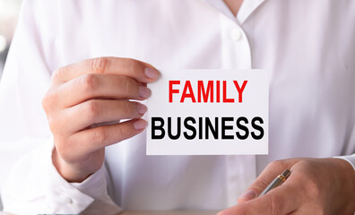 Closeup on businesswoman holding a card with text FAMILY BUSINESS, business concept image with soft focus background