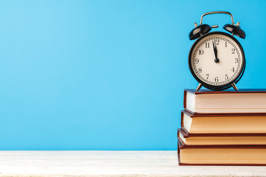 Books and alarm clock on table, education concept