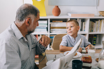 Obraz premium boy having breakfast at home with his grandfather