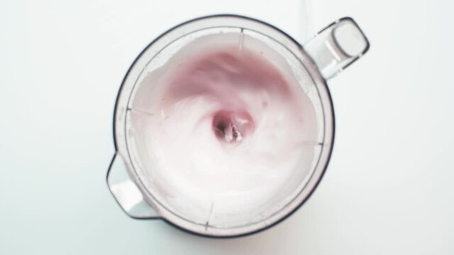 Top view of man touching blender with mixing smoothie on white
