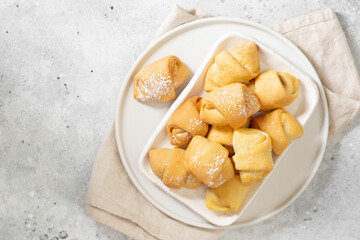 Lots of bagels. Puff pastry in a white plate on a light gray table. Cookies close-up. Top view with space for text	