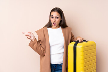 Traveler woman with suitcase surprised and pointing side