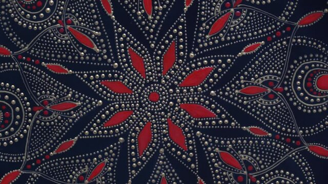 Decorative ceramic plate with black, red and golden colors, painted plate on background, closeup, top view, rotate. Decorative porcelain plate painted with acrylic paints, handwork, dot painting
