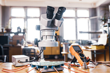 Fototapeta na wymiar Modern microscope, connectors component and large green microcircuit in workshop laboratory