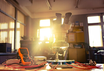 Modern microscope, connectors component and large green microcircuit in workshop laboratory
