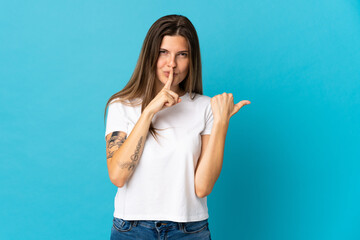 Fototapeta premium Young slovak woman isolated on blue background pointing to the side and doing silence gesture