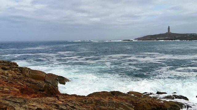 The Tower of Hercules in La Coru&ntilde;a from the other end of the bay and the sea alive