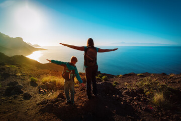silhouette of happy mother and son travel at sunset mountains