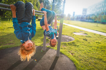 happy kids upside down on monkey bars outdoors