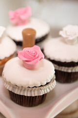 Fresh delicious cupcakes with white sugar garnish and pink sweet flower on top