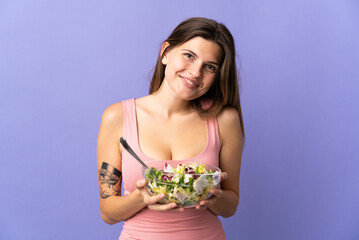 Young slovak woman isolated on purple background holding a bowl of salad with happy expression