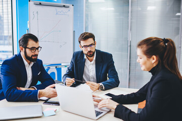 Successful male and female colleagues making laptop booking during collaborative meeting, Caucasian business partners discussing startup projecting reading financial news via netbook application