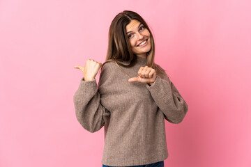 Young slovak woman isolated on pink background pointing to the side to present a product