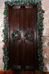 Fototapeta na wymiar Christmas wreaths and decoration on the doors of the house