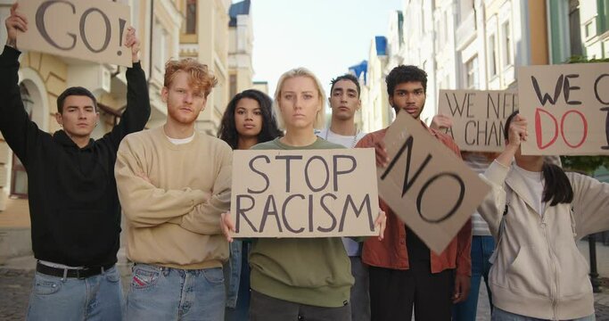 Public demonstration at street against racism with slogans on posters. Multiethnic people protest.