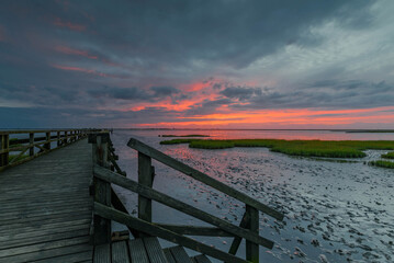Wooden plank footbridge and bathing area on the North sea by sunset